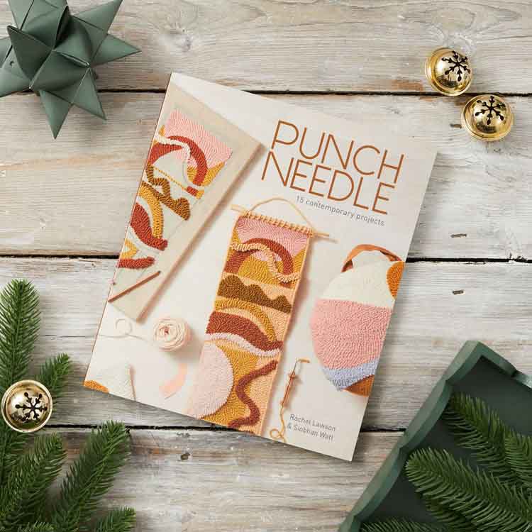 Punch needle craft book on a wooden surface with decorative elements