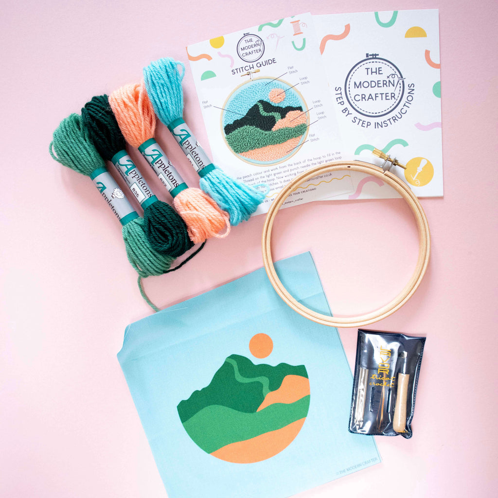 Punch Needle Embroidery kit with threads, hoop, and pattern on a pink background