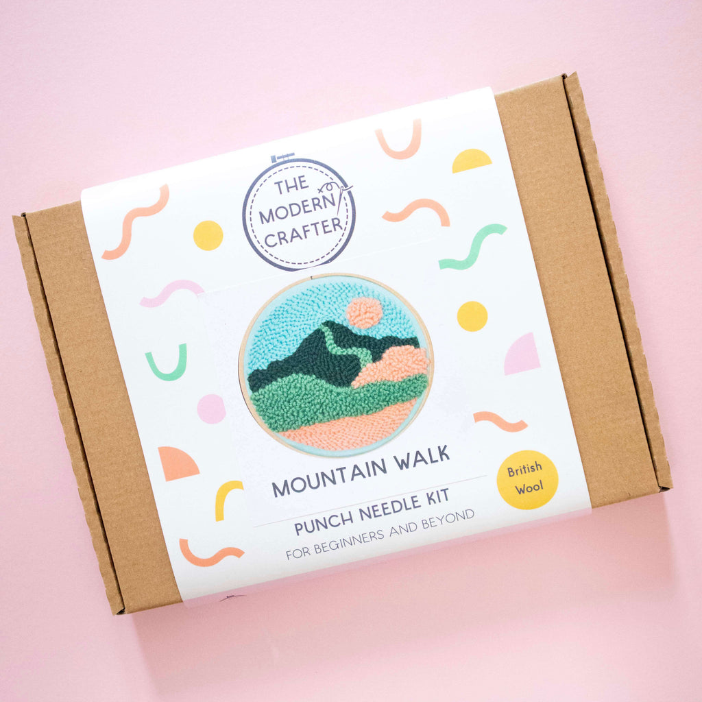 Punch needle kit packaging with mountain design on a pink background