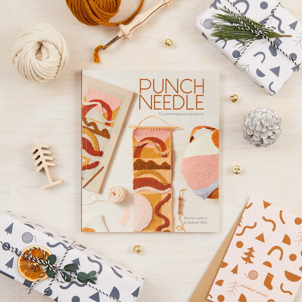 Punch needle book with yarn and tools on a light surface